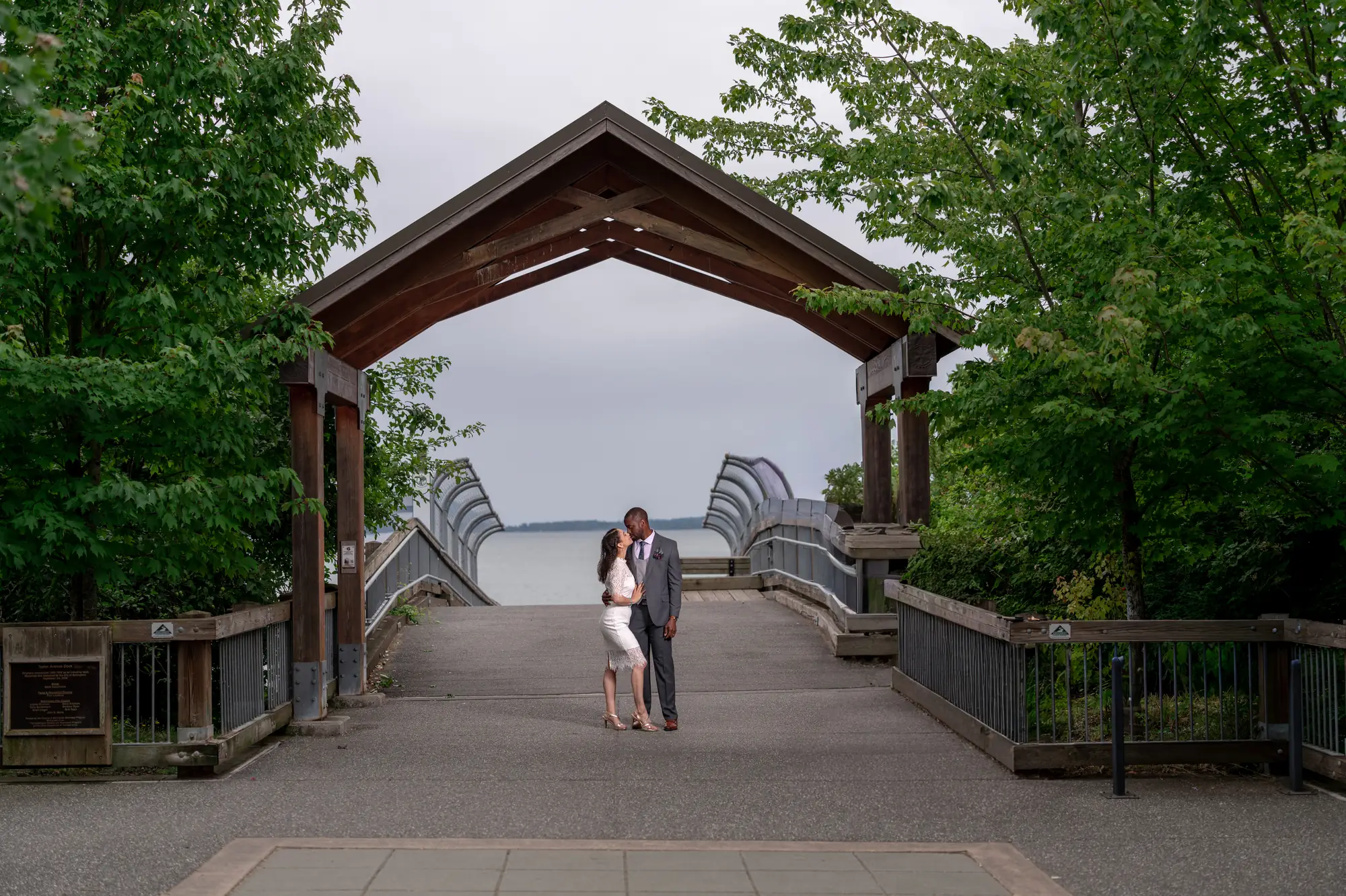 Newlyweds kissing under a wooden waterfront archway at their Washington elopement