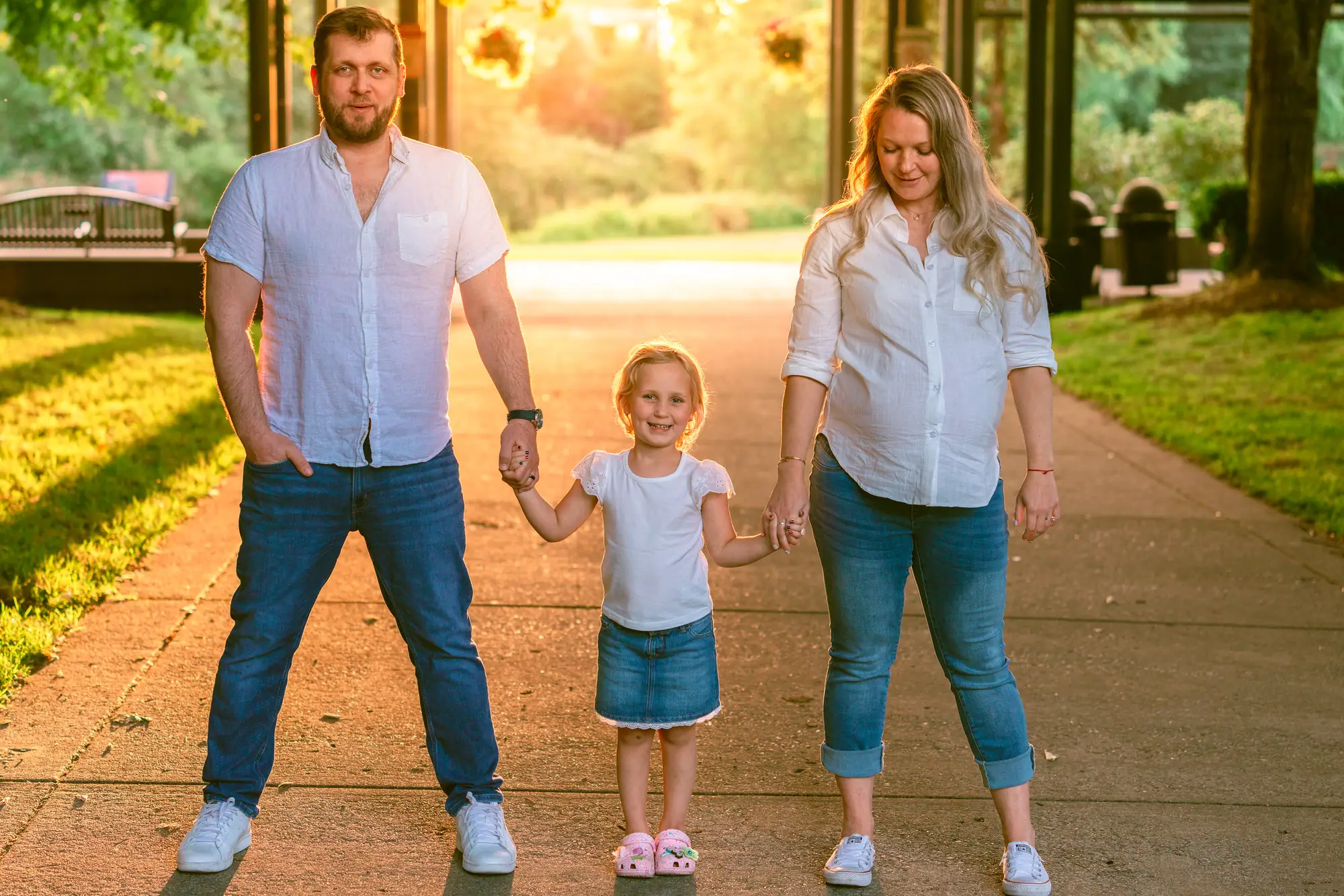 Expecting family holding hands at golden hour during a maternity session