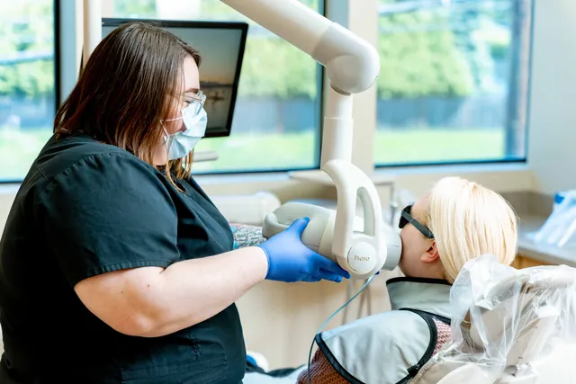 Dental team member in a mask working with a patient reclined in the chair