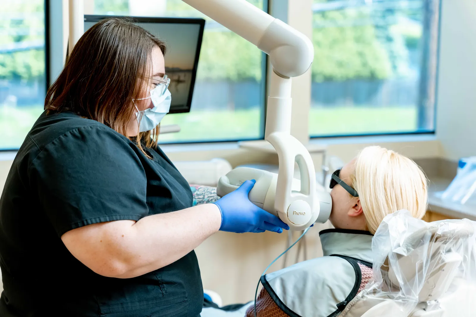 Dental team member in a mask working with a patient reclined in the chair