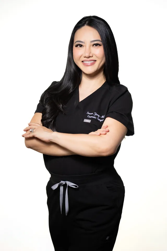 Aesthetic injector in black scrubs with arms crossed, branding portrait on white