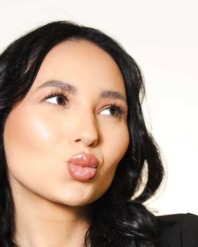 Close-up beauty portrait of an injector blowing a kiss, glossy lips and lashes in focus