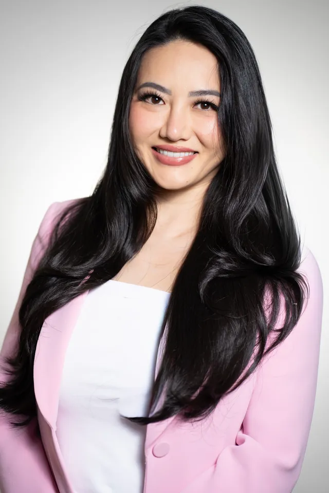 Aesthetic injector in a pink blazer and white top, branding portrait on a white backdrop