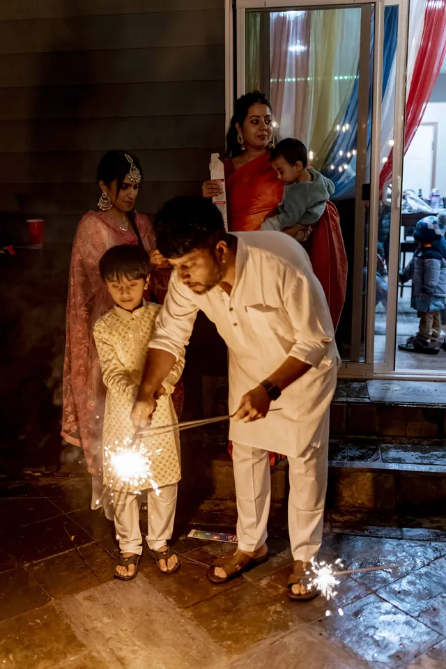 Father and son lighting sparklers together on Diwali night