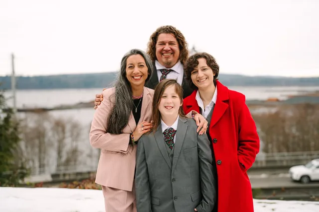 Family of four in winter coats and suits on the snowy Lake Stevens waterfront