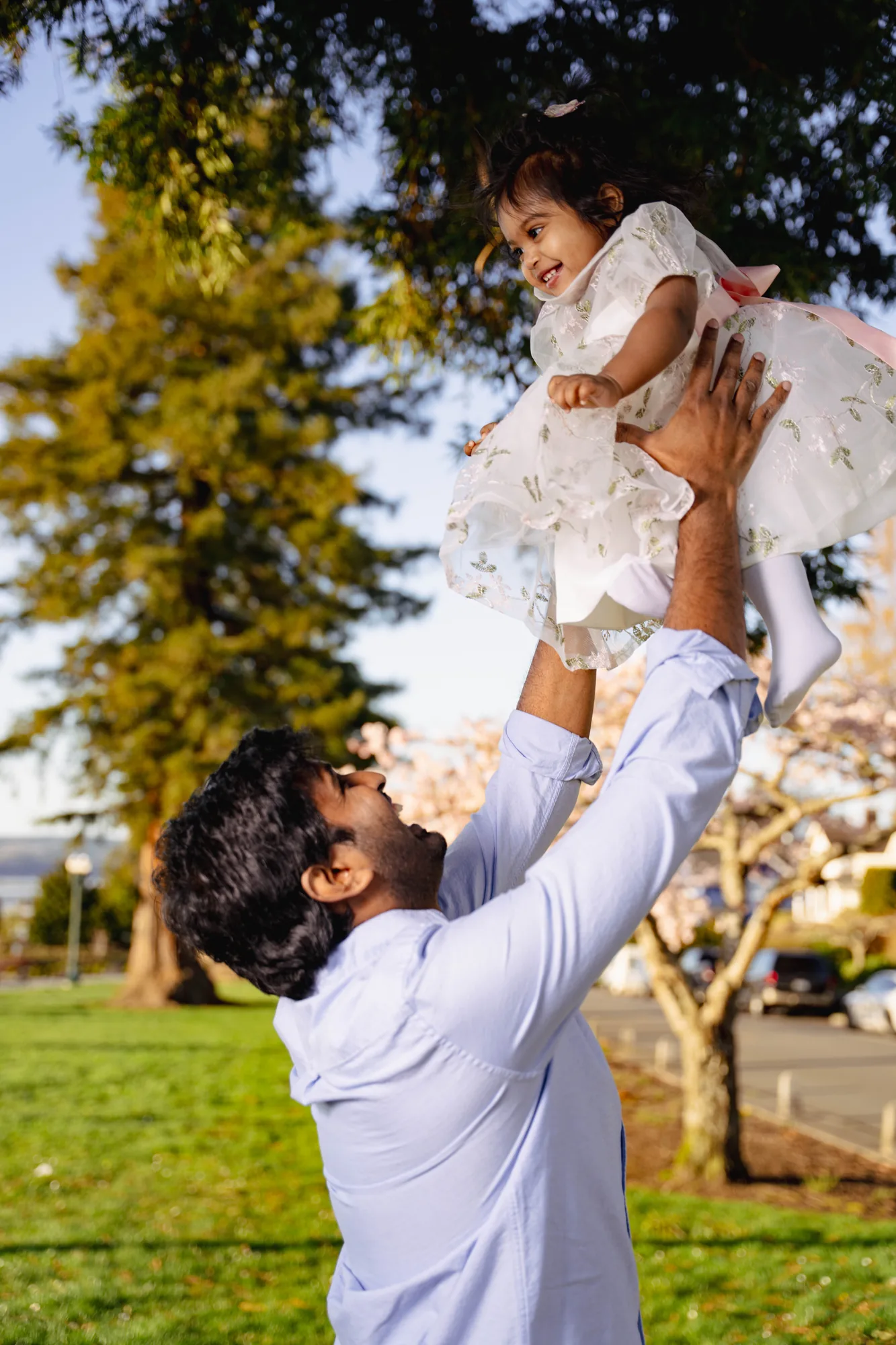 Father lifting daughter into air under cherry blossoms in Snohomish County family session