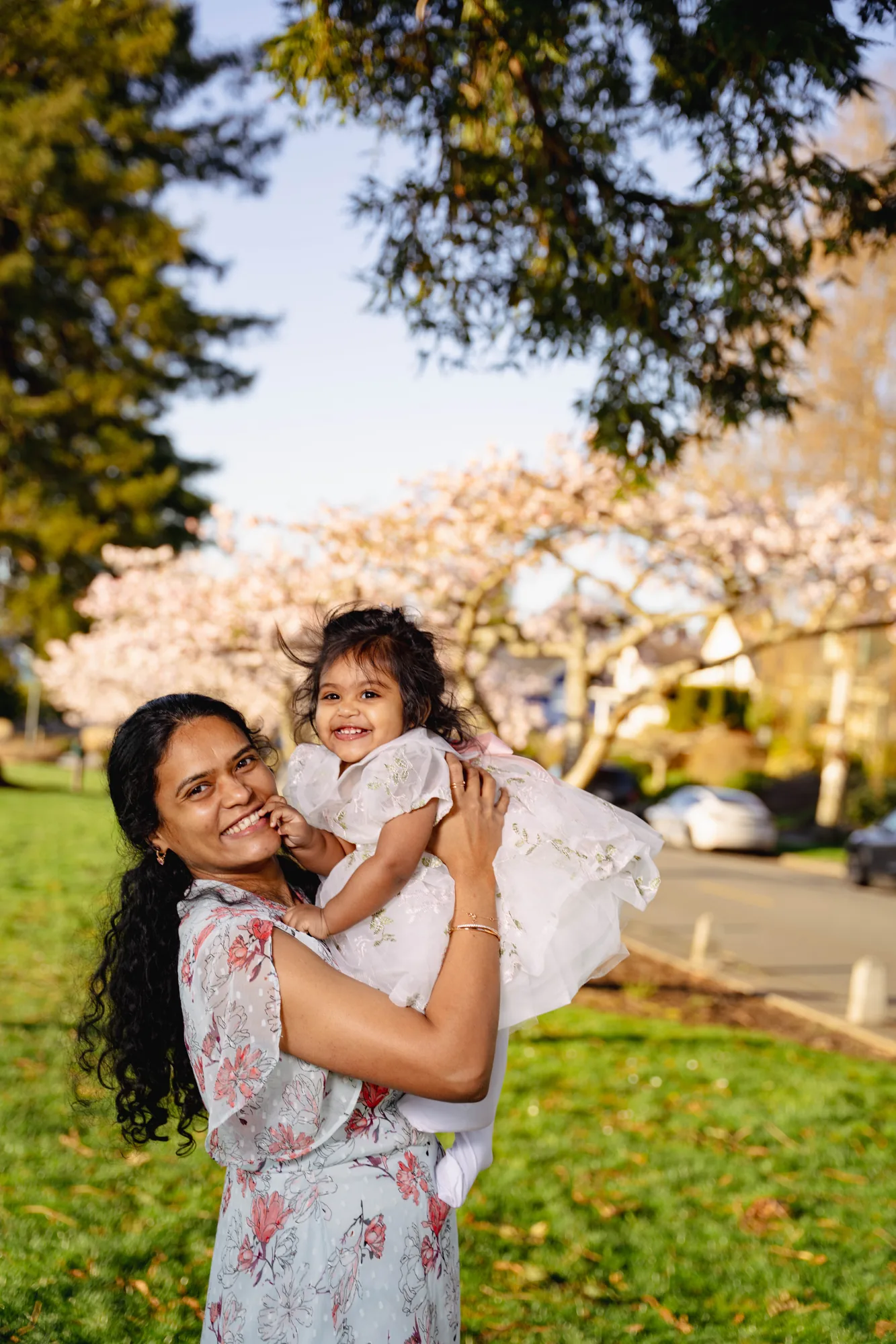 Mother hugging her daughter among cherry blossoms
