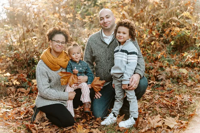 Family of four kneeling in fallen maple leaves in Snohomish County
