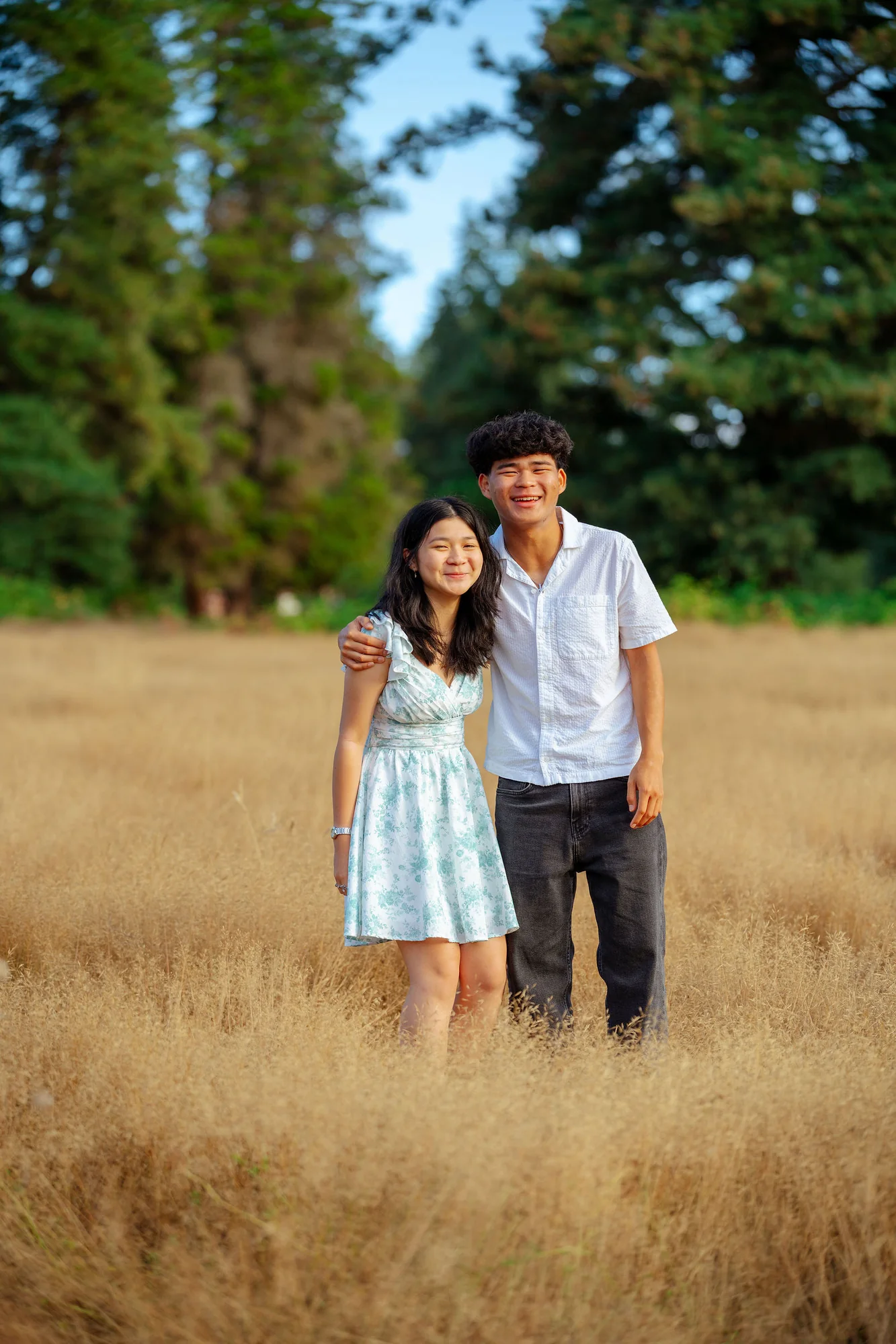 Siblings laughing together in tall golden grass