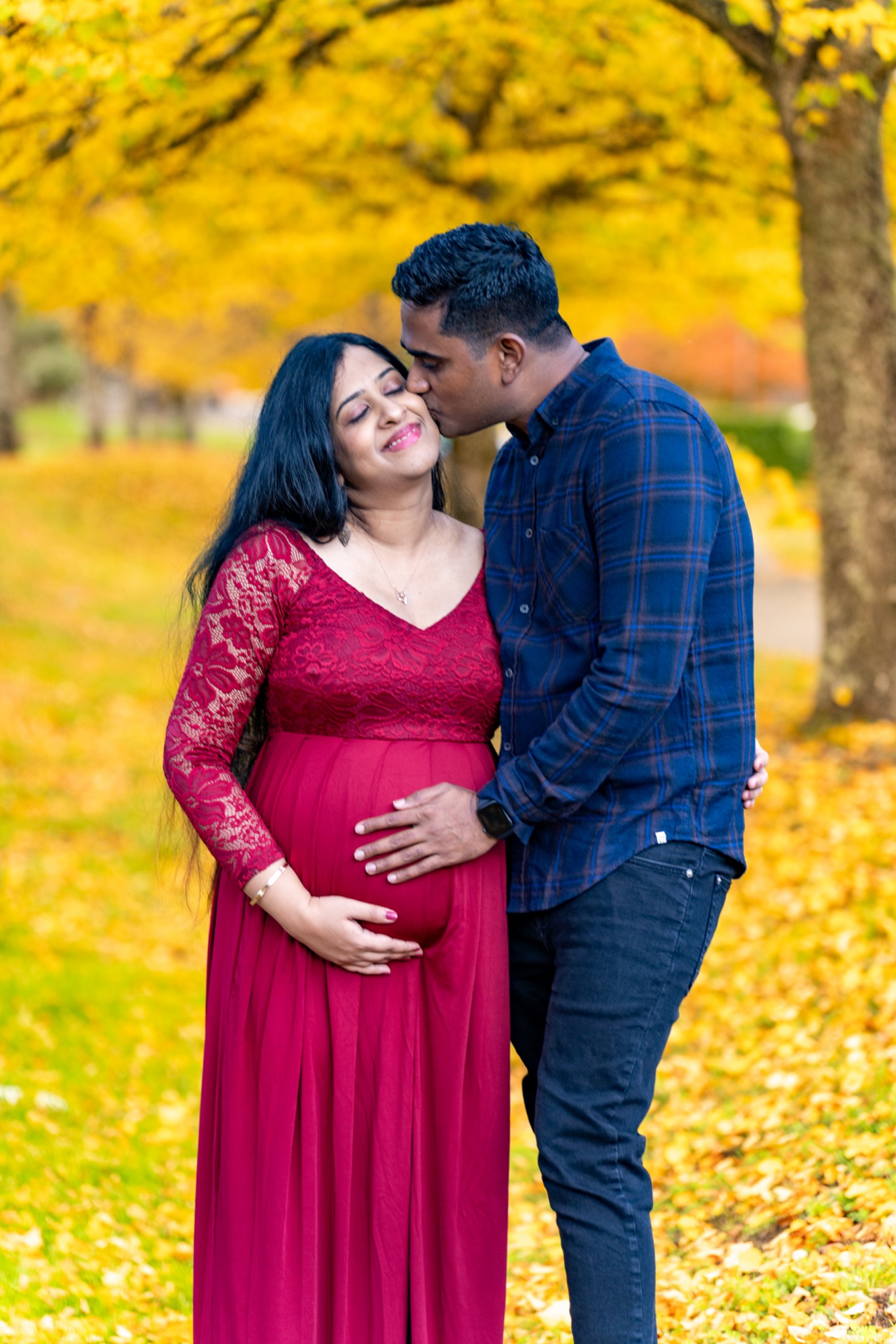 Expecting couple kissing in autumn foliage during Bothell maternity session