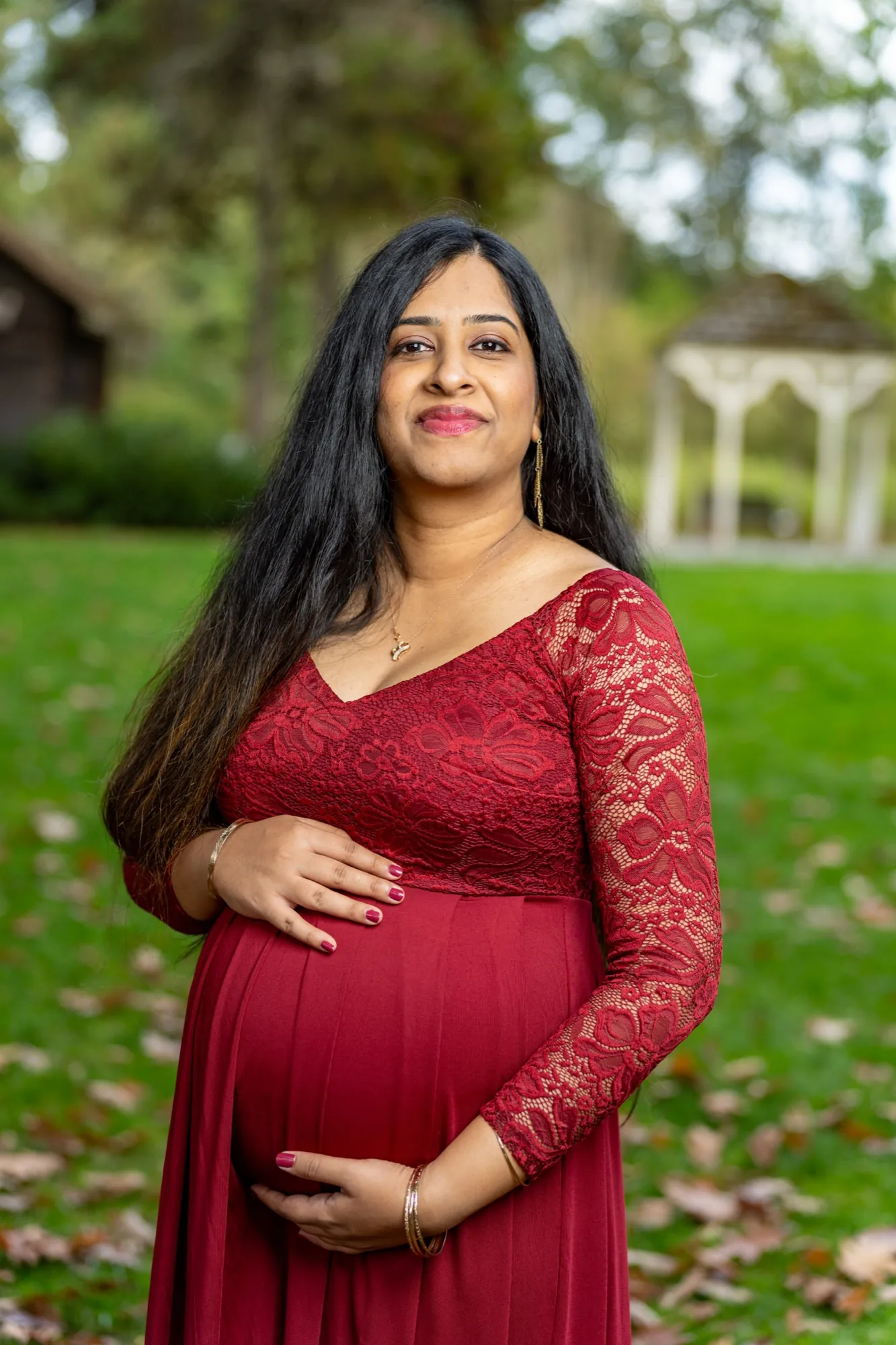 Expecting woman in red dress at park gazebo in Bothell WA