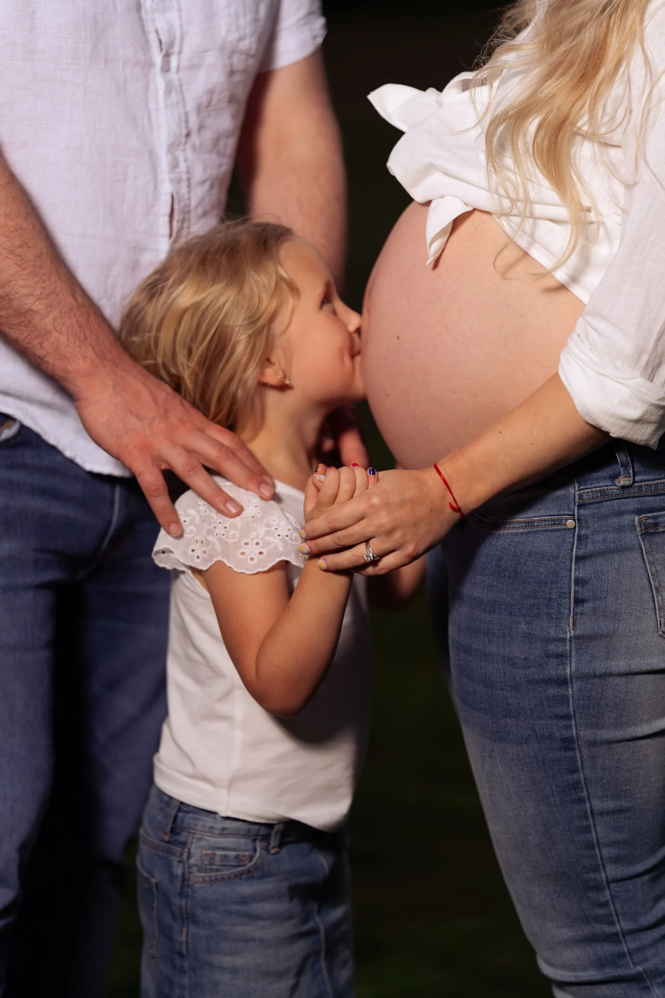 Big sister kissing mom's baby bump during a golden hour maternity session