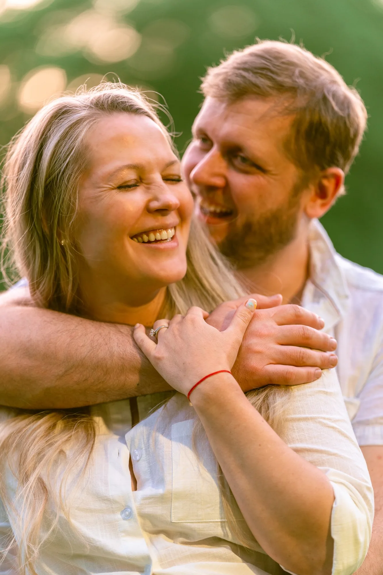 Expecting mother laughing in her husband's embrace at golden hour