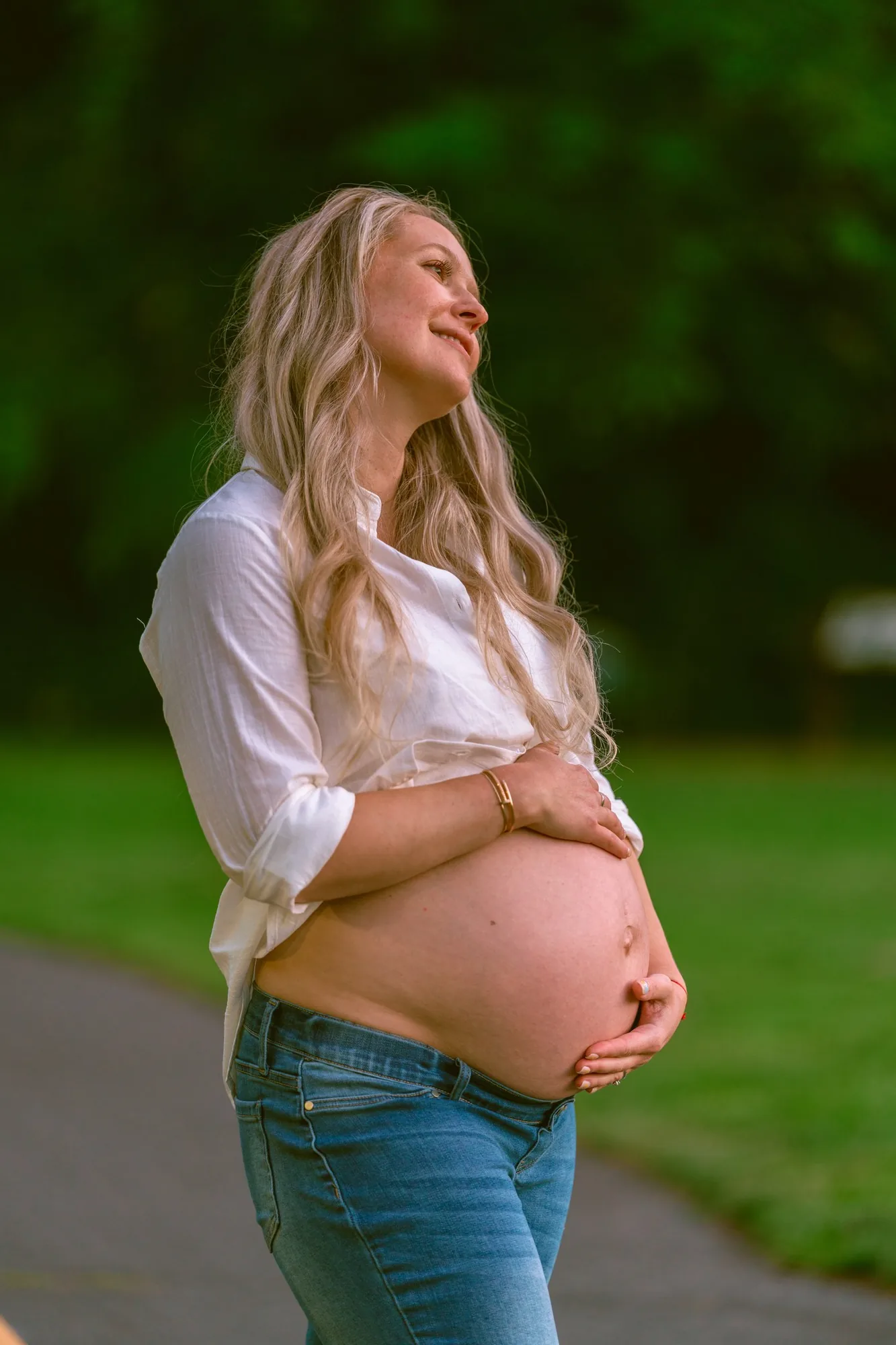 Expecting mother cradling her bump in golden evening light