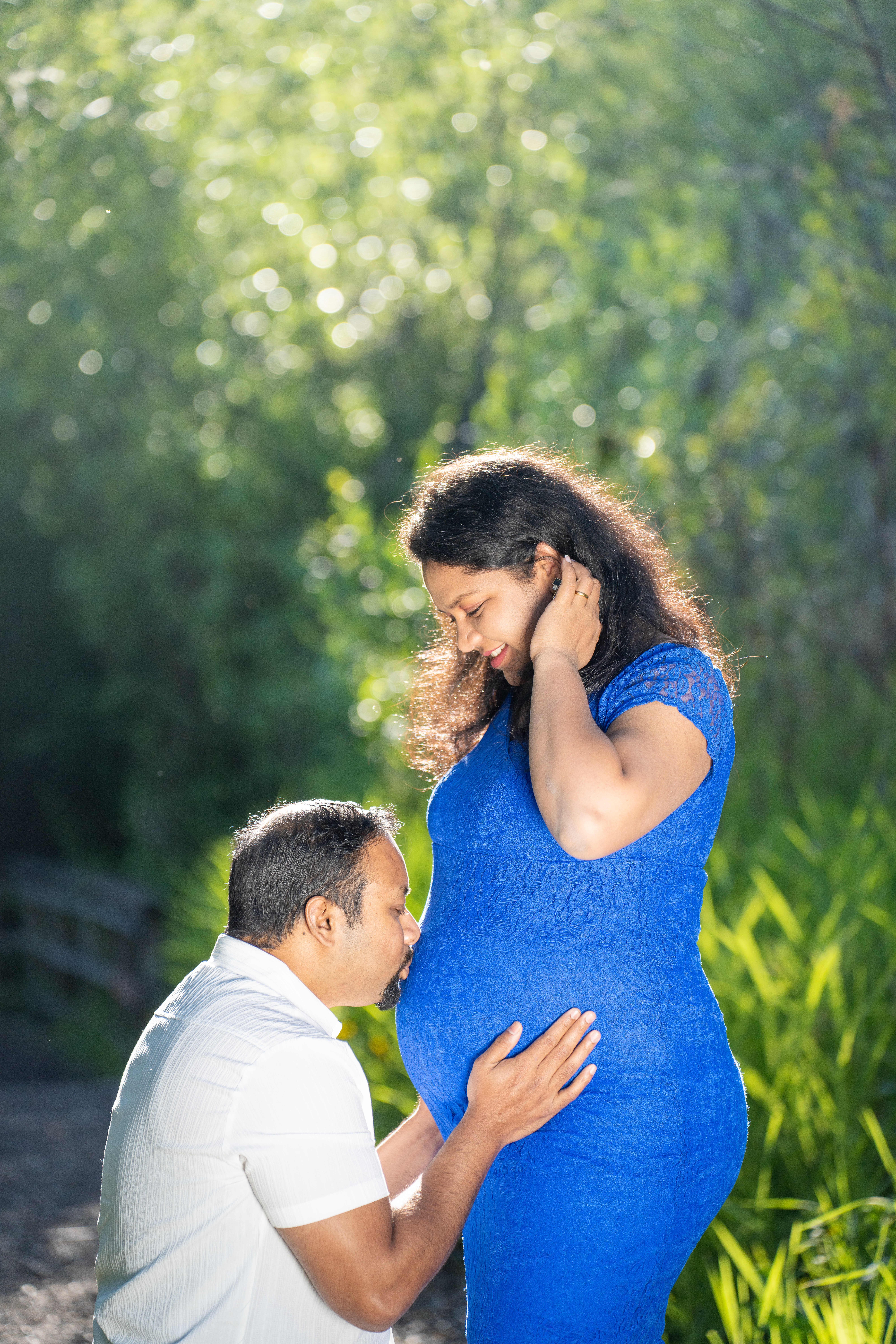 Expecting couple sharing kiss with blue dress over belly in Snohomish County