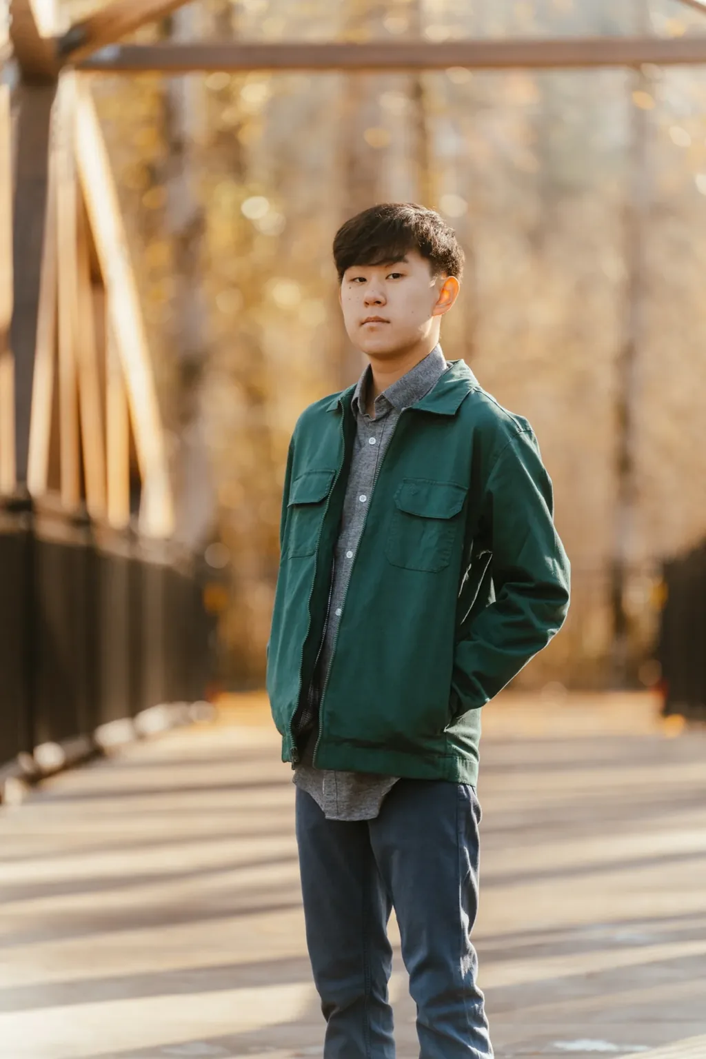 Senior in a green jacket on a wooden truss footbridge in Lake Stevens in autumn light