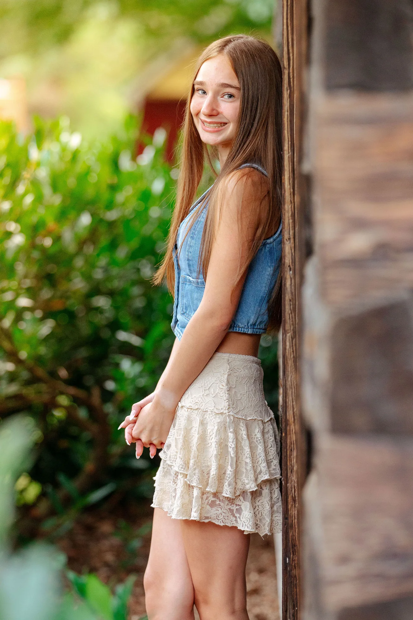 Senior portrait in warm evening light, leaning against brick