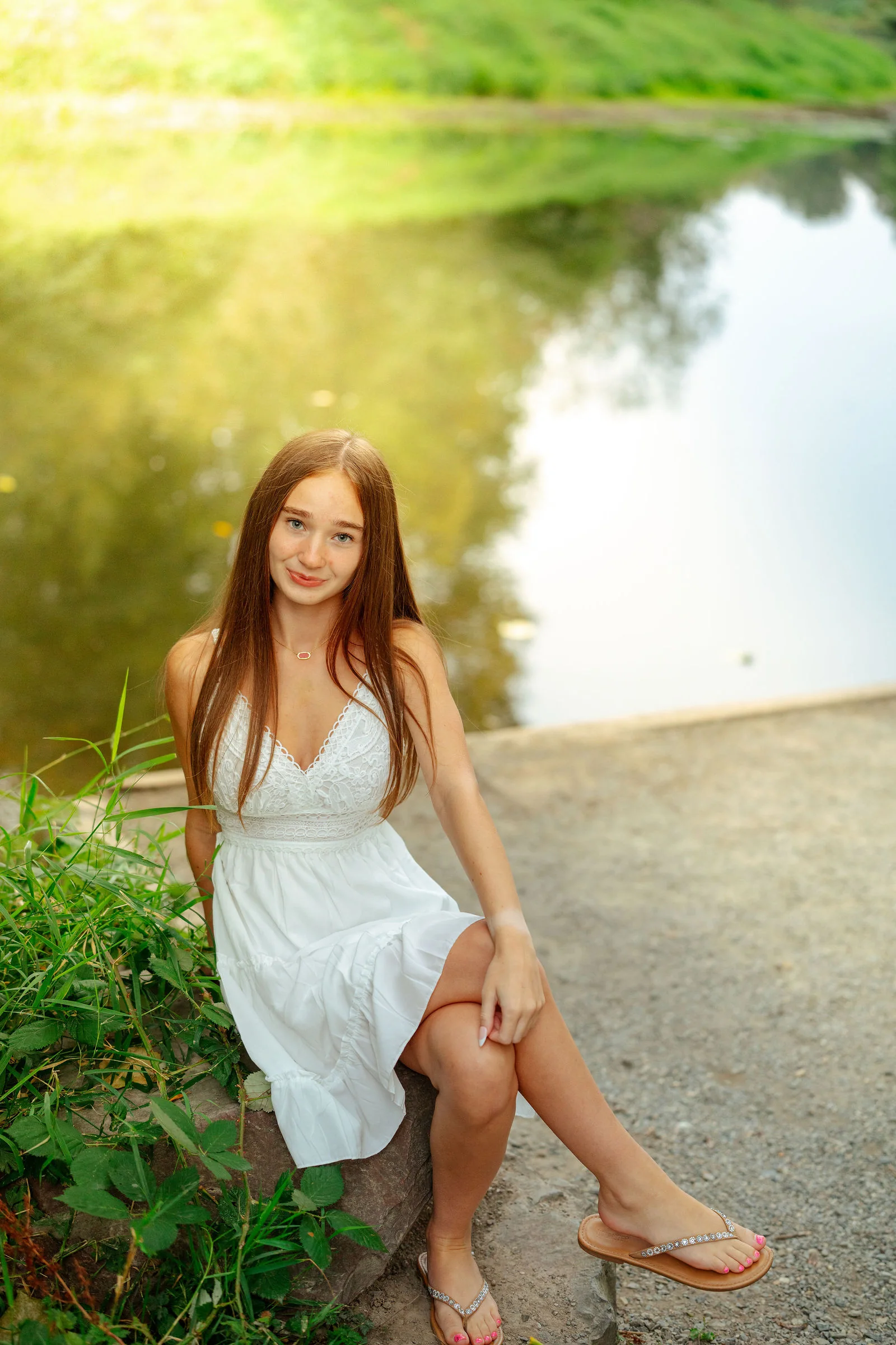 Senior seated beside the water in a white dress