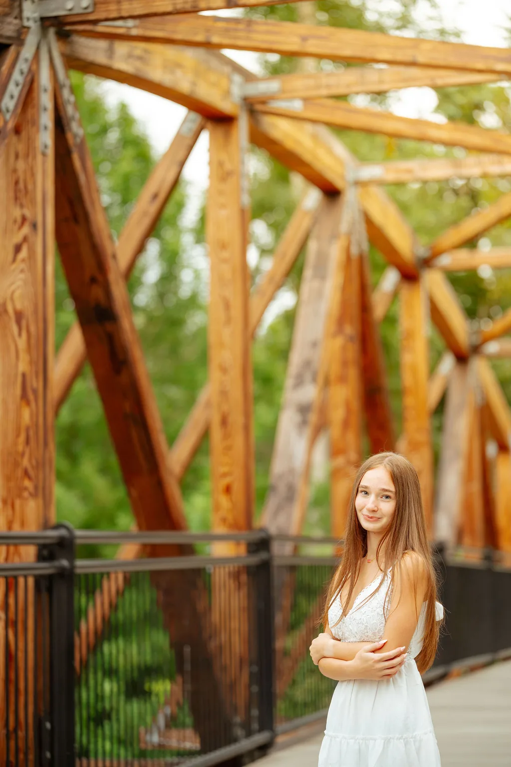 Senior in a white dress on a timber truss footbridge in Lake Stevens in summer