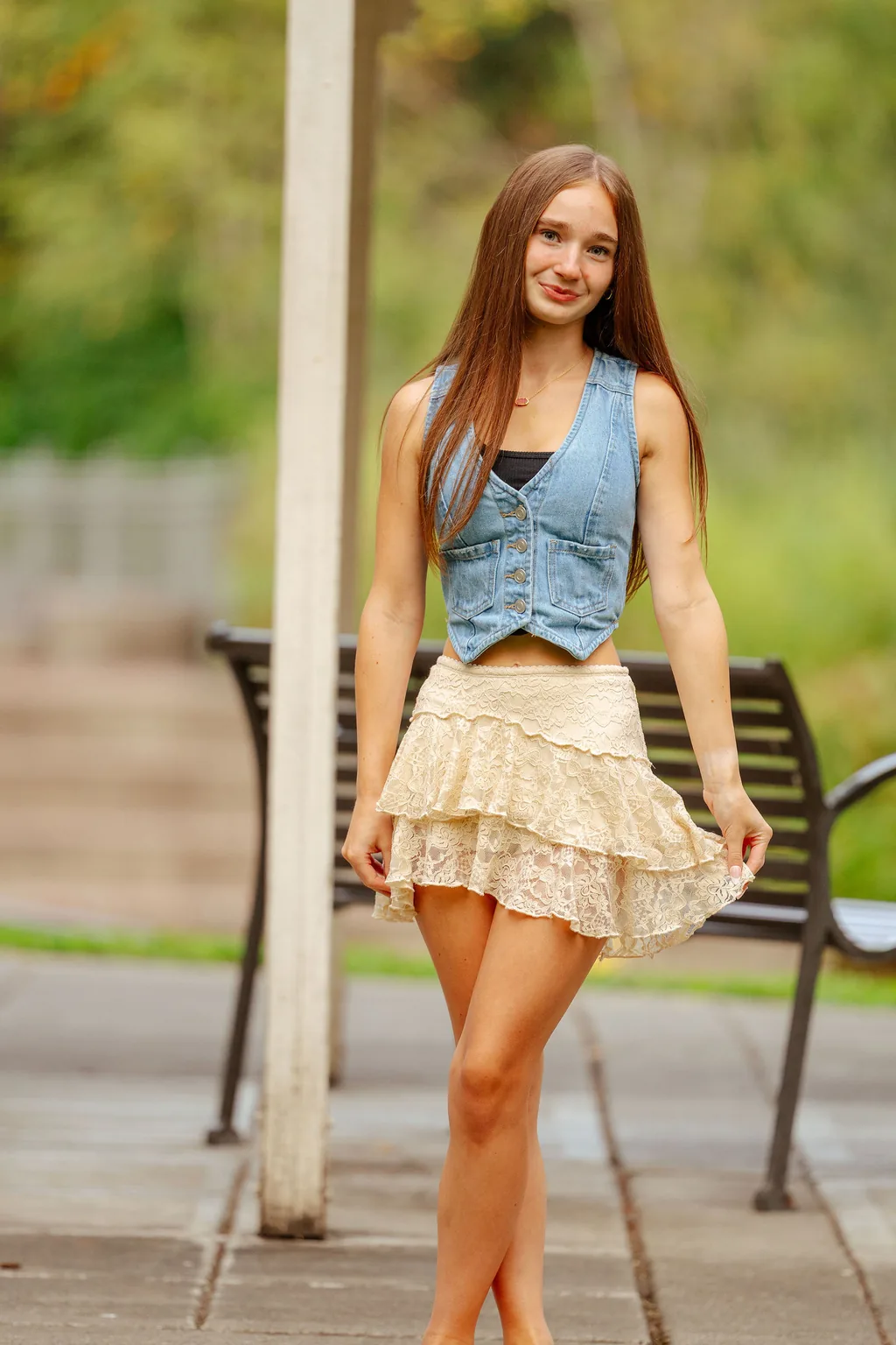 Senior in a denim vest and lace skirt walking a paved park path in Lake Stevens