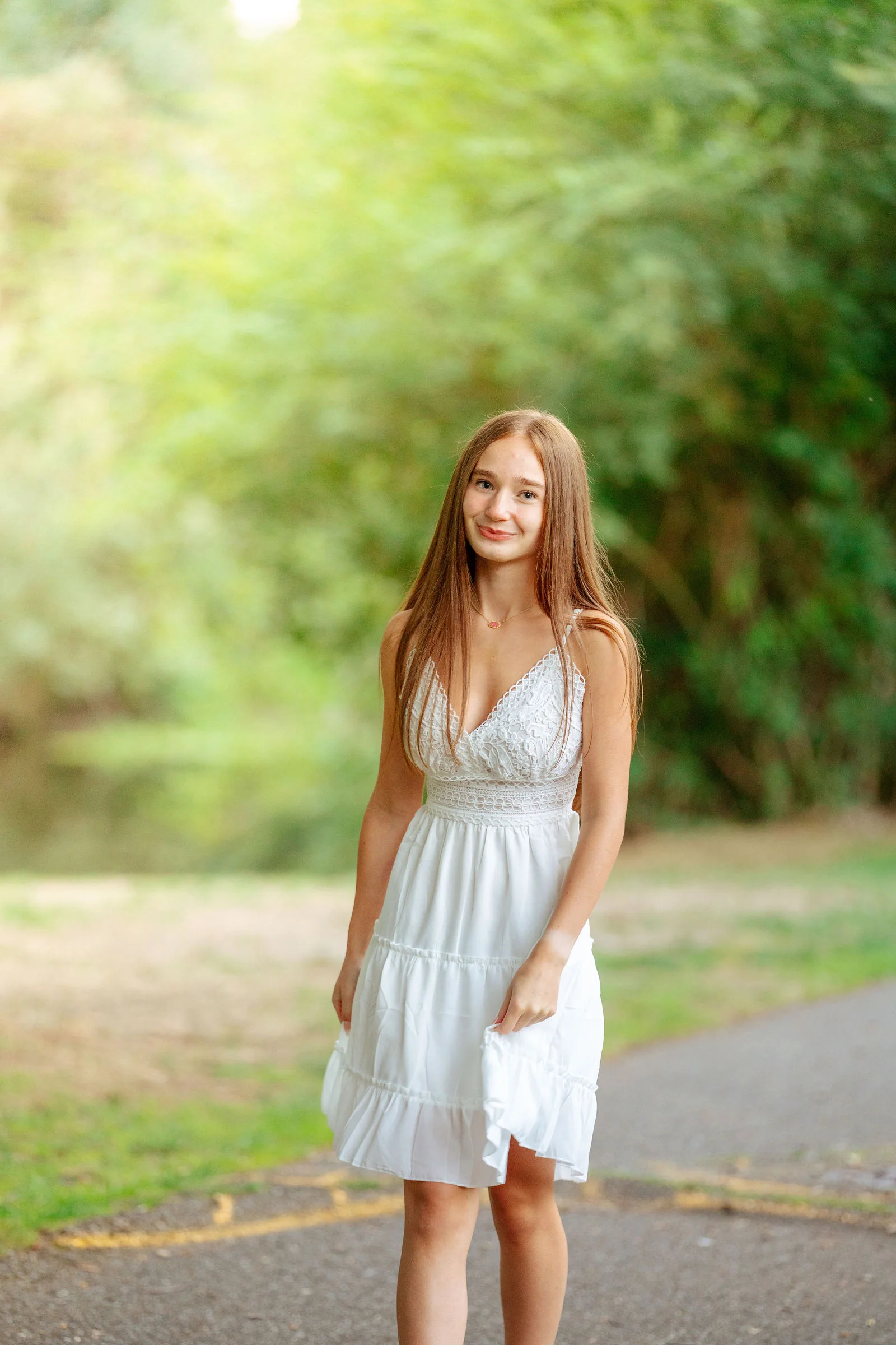 Senior in a white dress on a green summer path