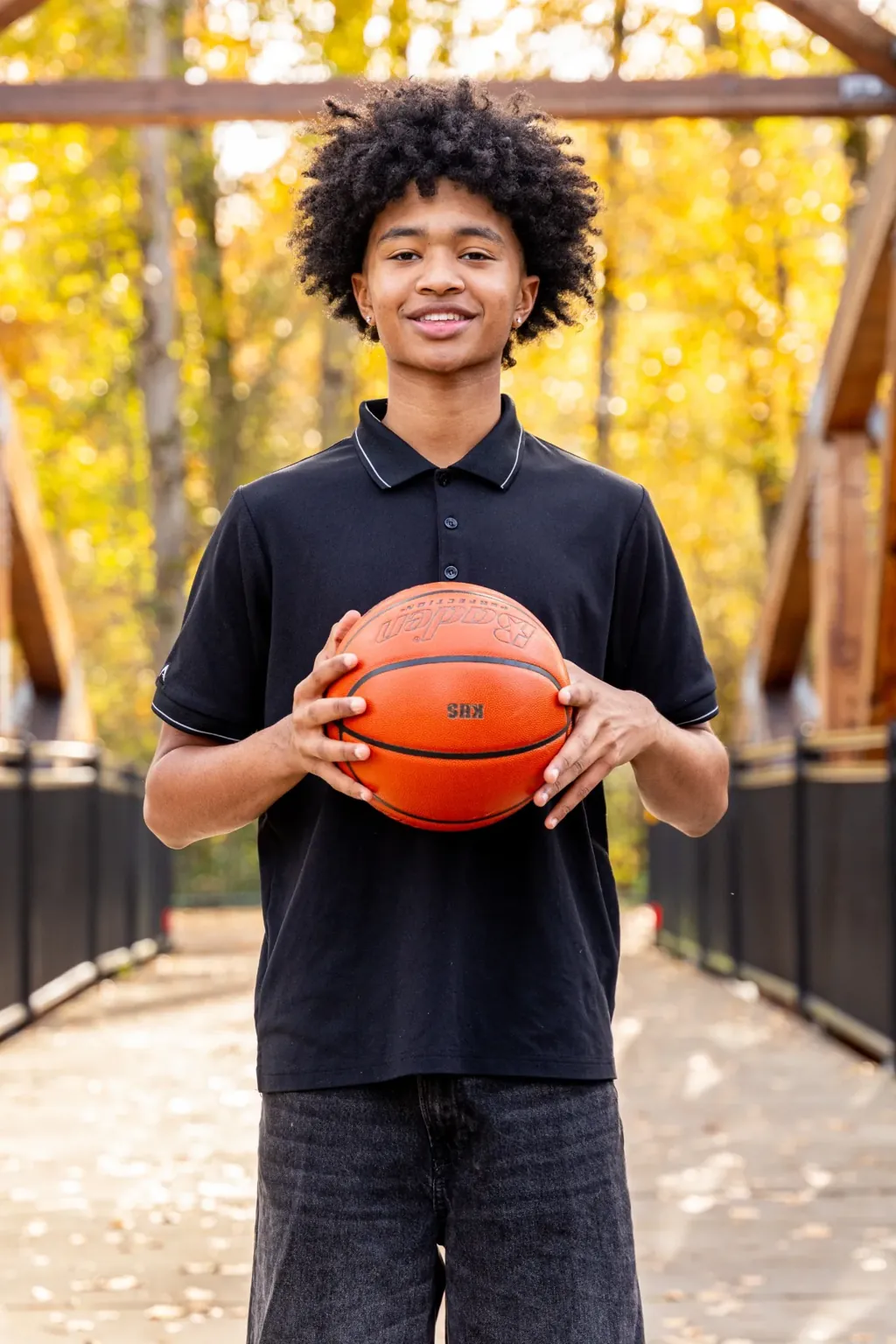 Senior holding a basketball on a wooden footbridge in autumn