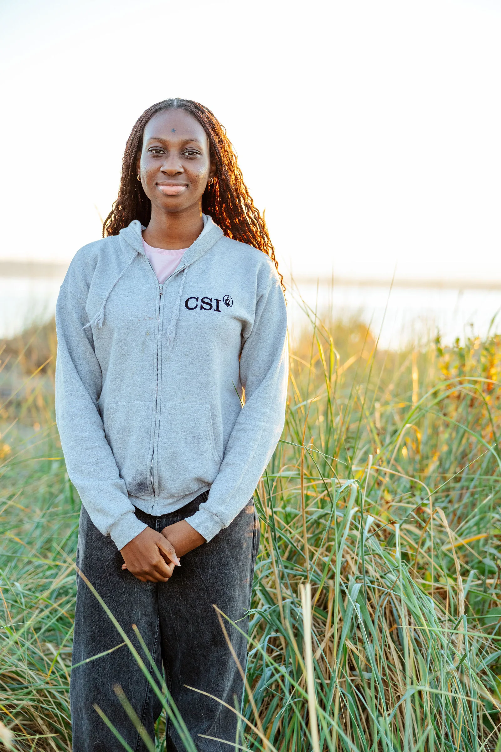Senior portrait in beach dune grass at golden hour