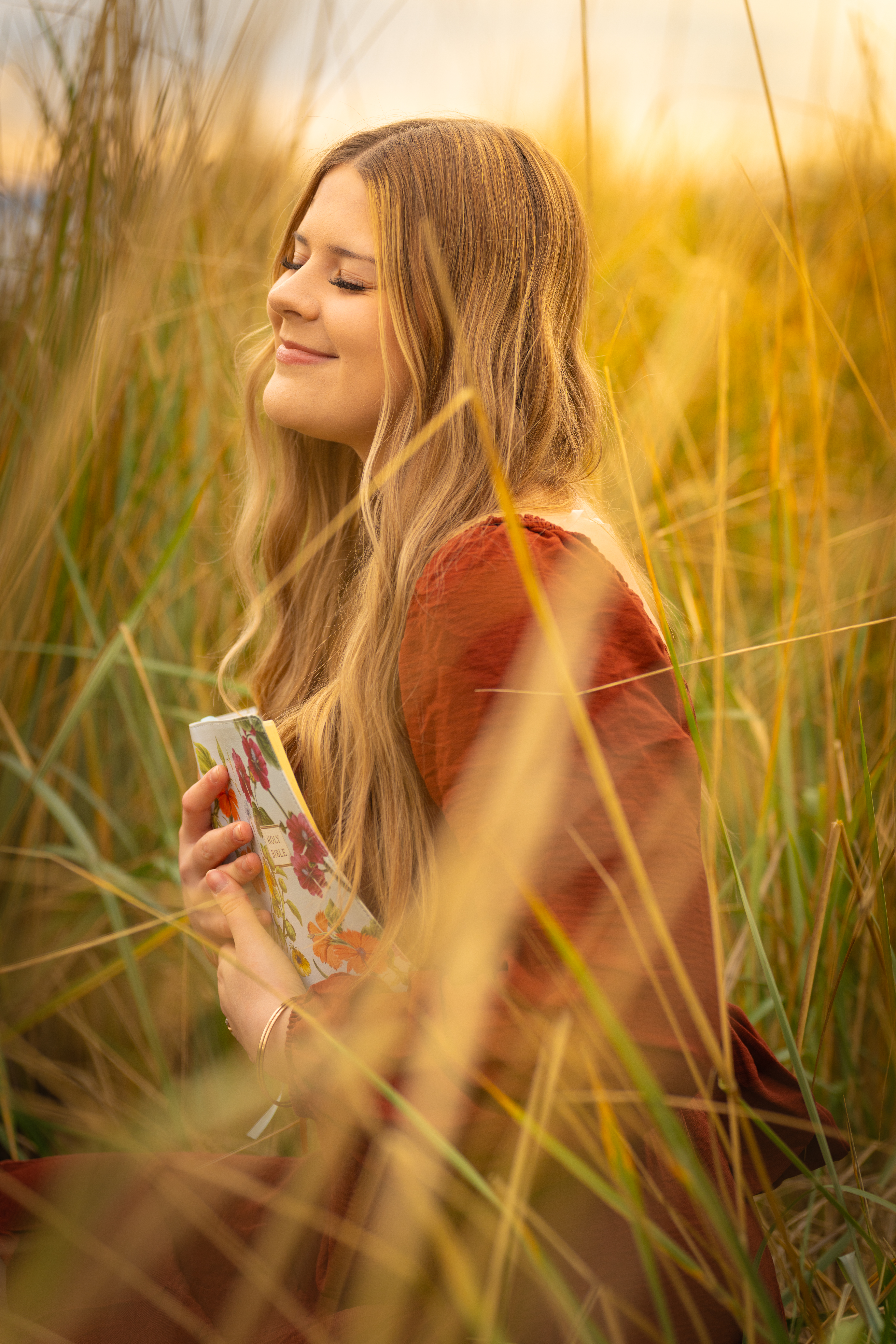 High school senior with book in golden grass field in Lake Stevens WA