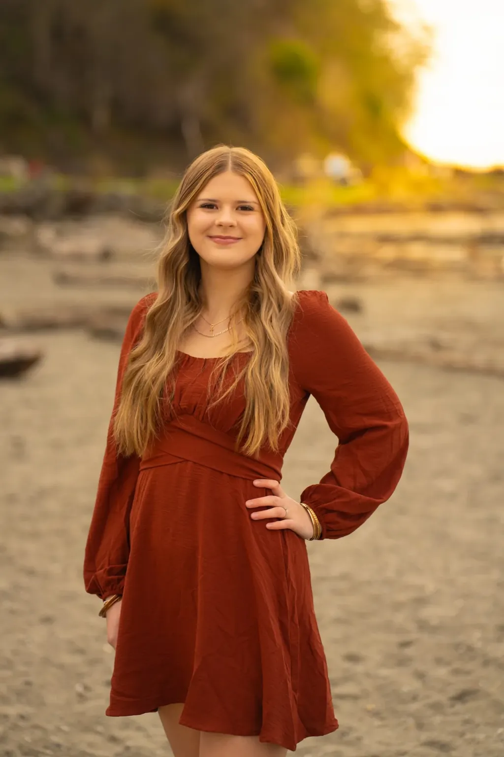 Senior in a rust dress on a beach at golden hour