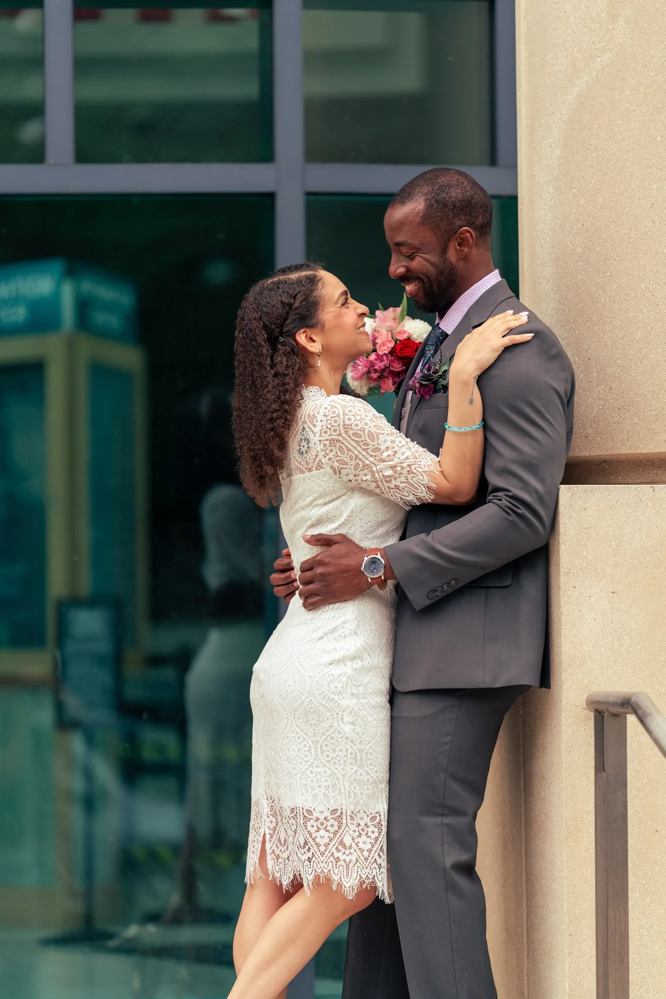 Bride with bouquet embracing her groom outside the courthouse