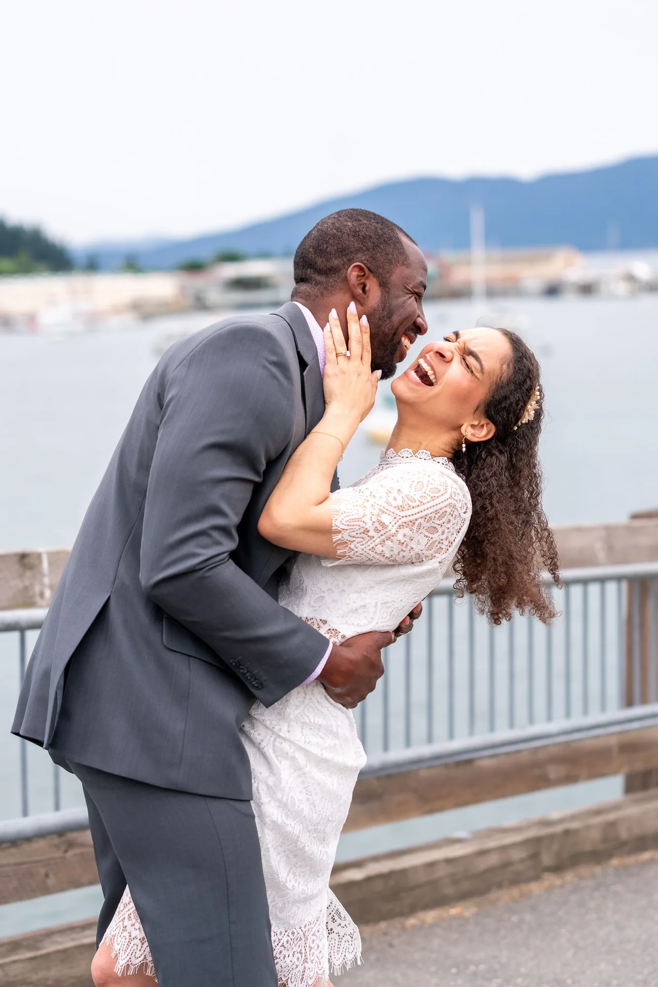 Groom dipping his laughing bride on the marina waterfront after their elopement