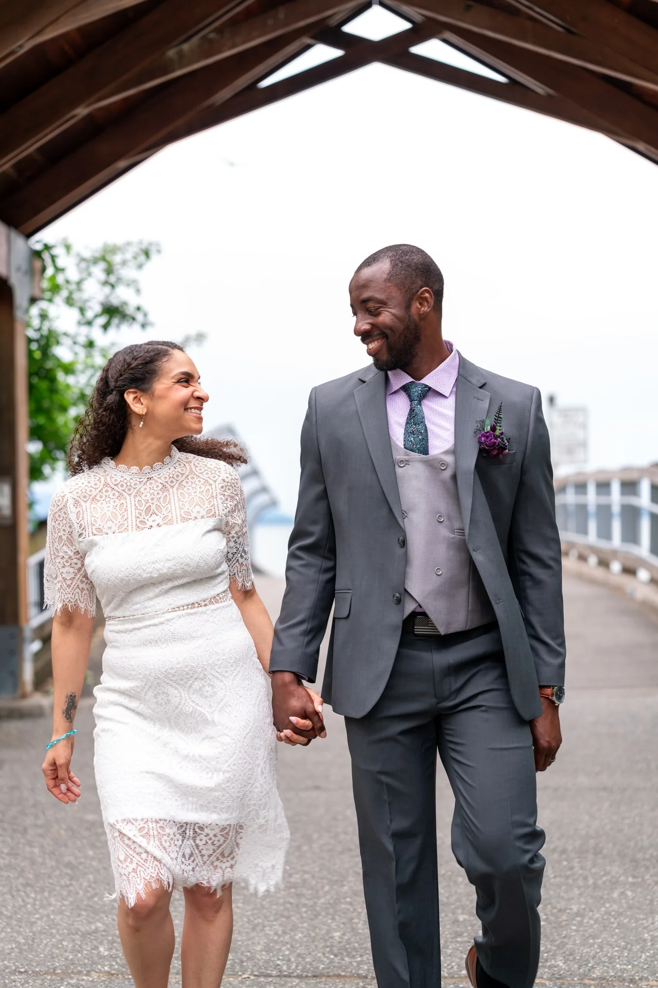 Newlyweds walking hand in hand along the waterfront boardwalk after their courthouse elopement
