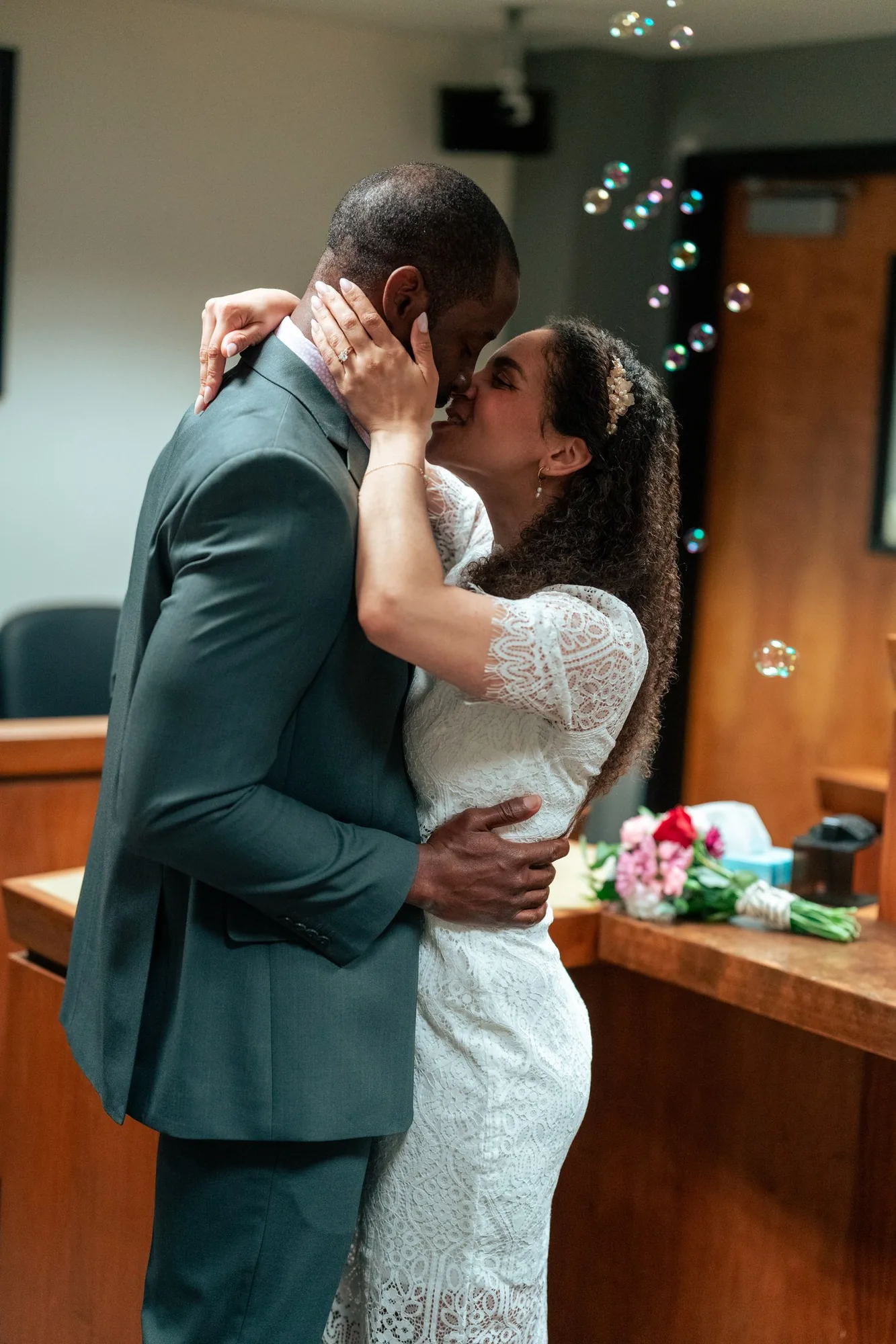 First kiss as newlyweds with bubbles floating in the courtroom