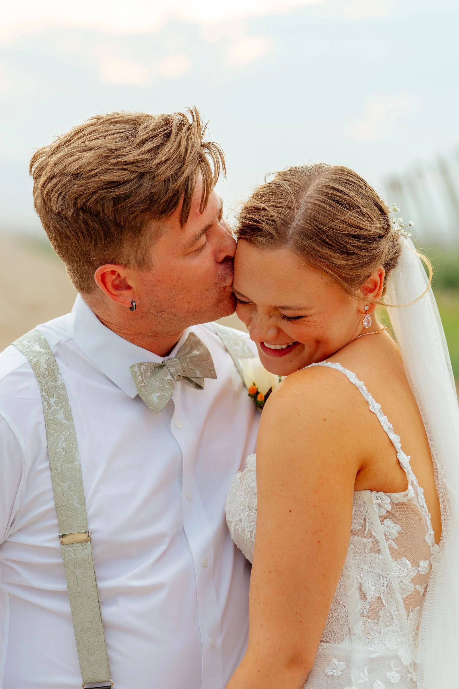 Groom kissing his bride's cheek as she laughs
