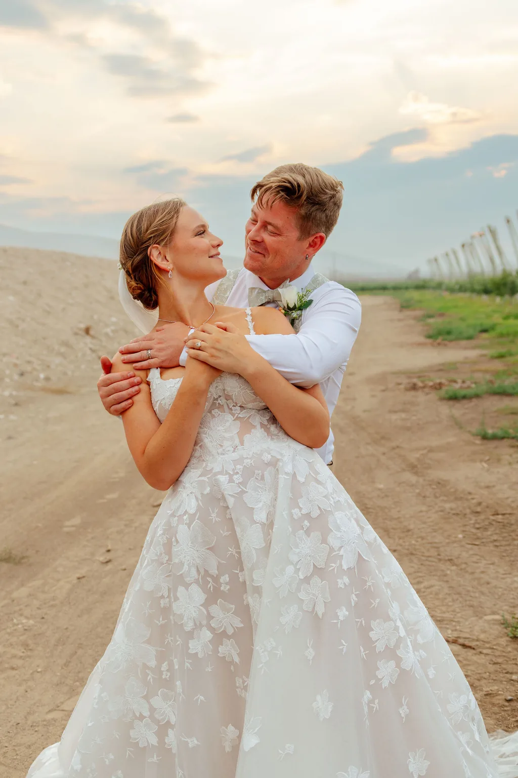 Bride and groom embracing in an orchard at golden hour on their wedding day