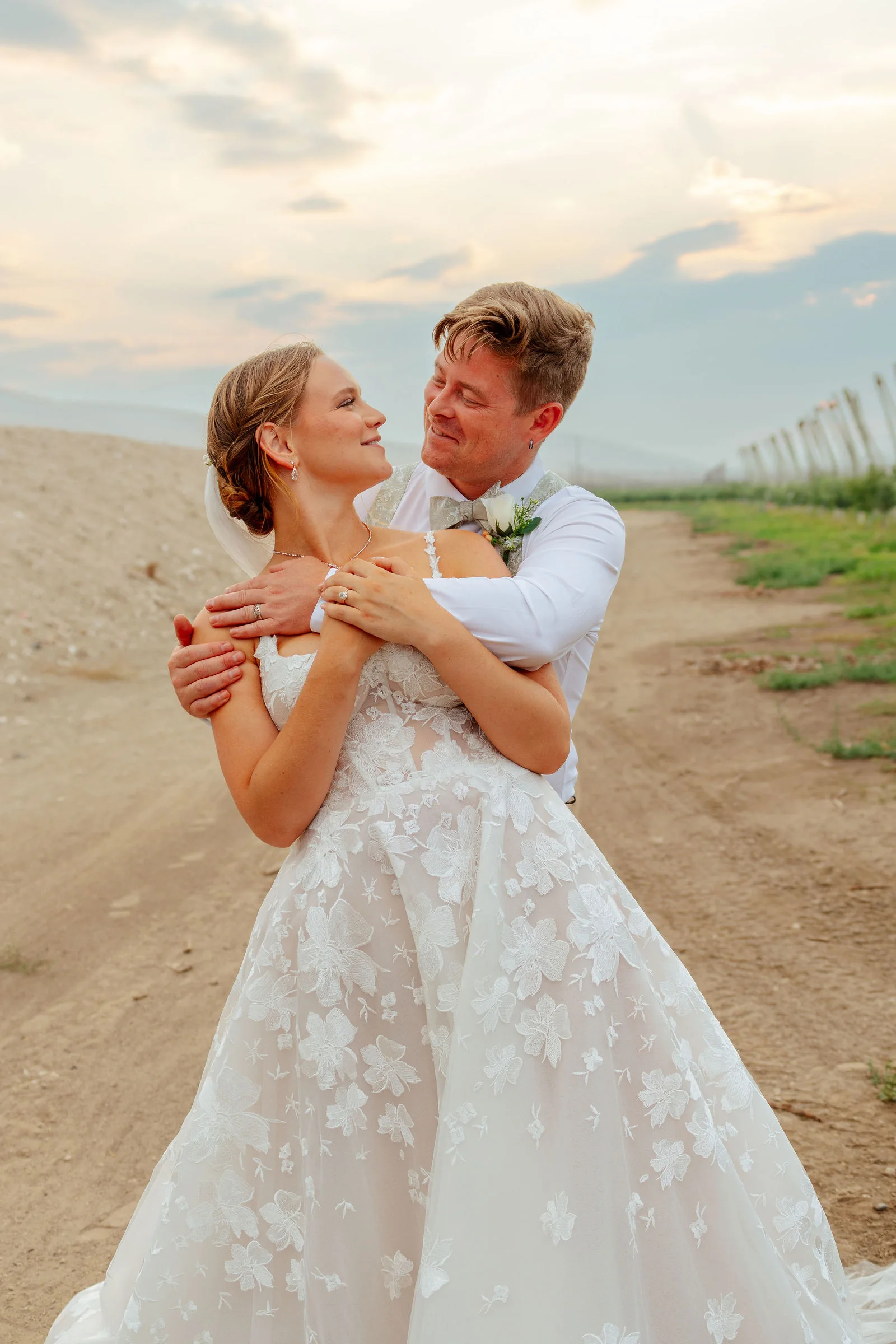 Bride and groom embracing in golden light at an orchard wedding