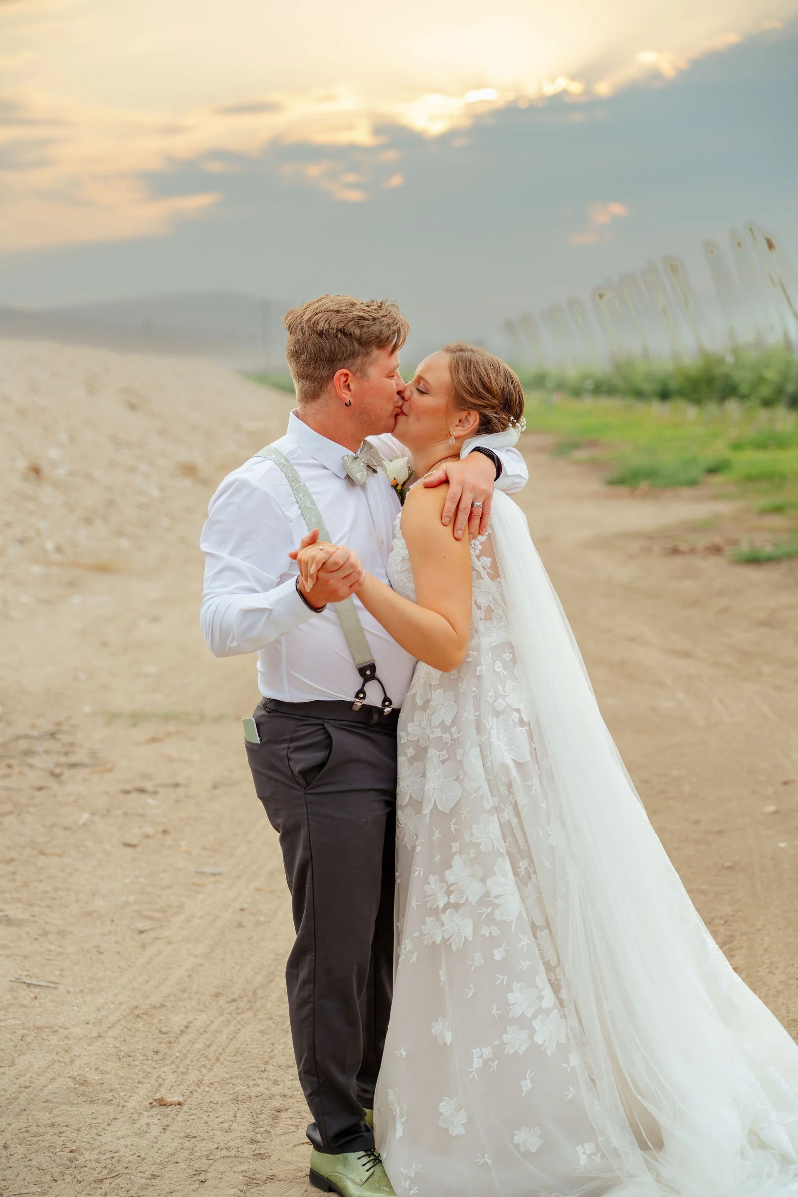 Bride and groom kissing as the sun drops behind the orchard