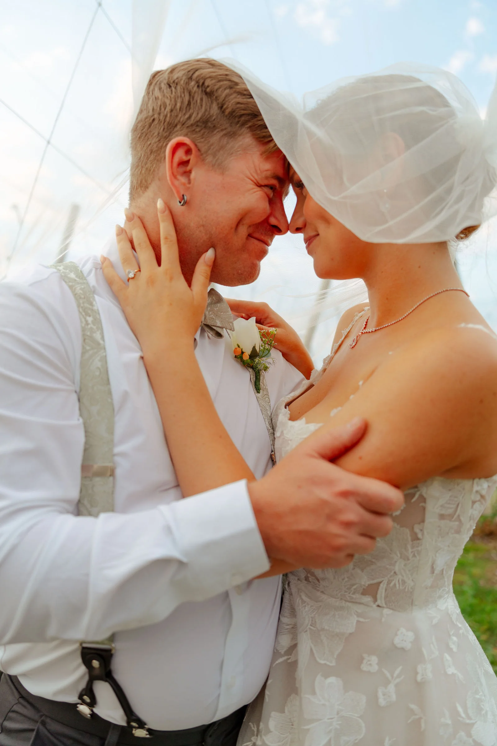 Bride and groom forehead to forehead beneath her veil