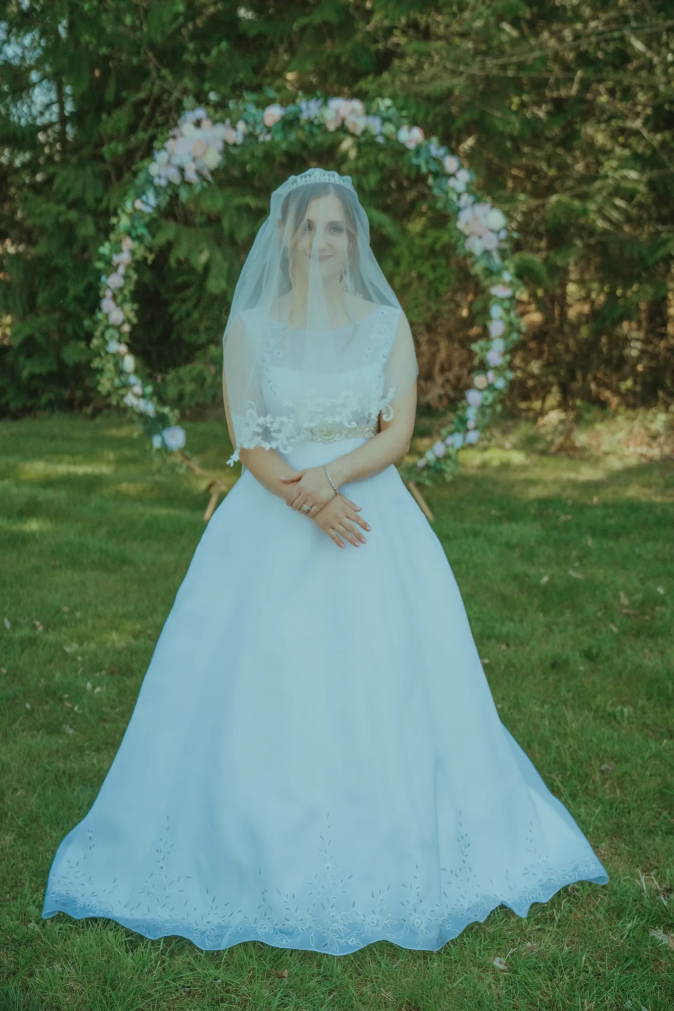 Bride full-length portrait in front of floral arch at Snohomish County wedding