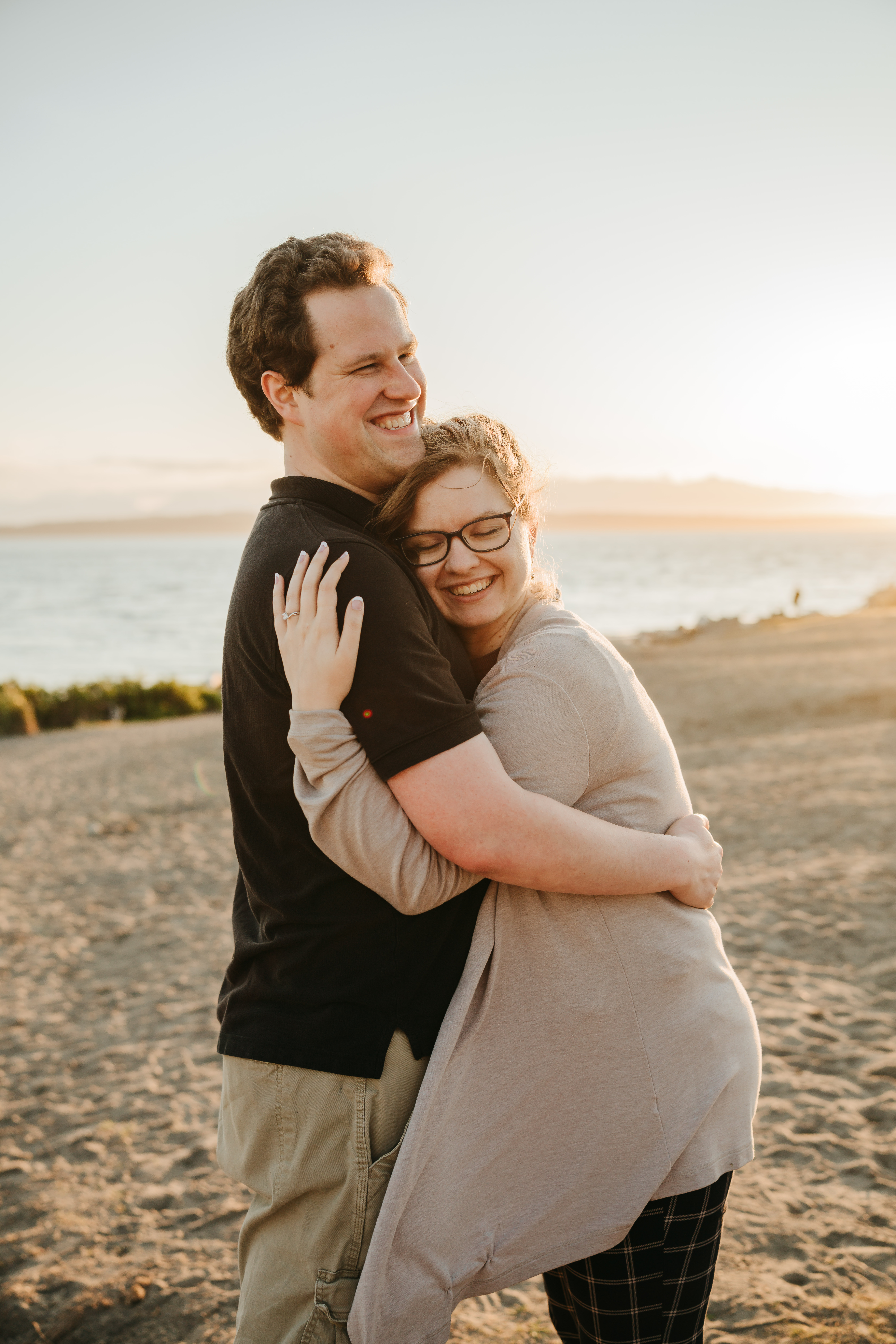Engaged couple hugging on beach at sunset in Snohomish County