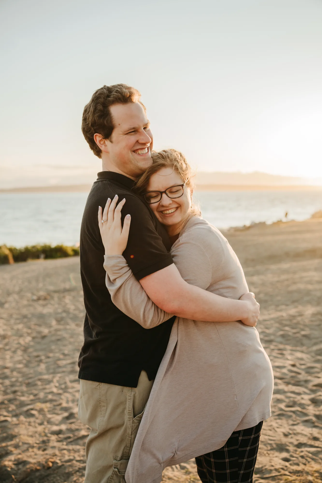 Engaged couple hugging on beach at sunset in Snohomish County