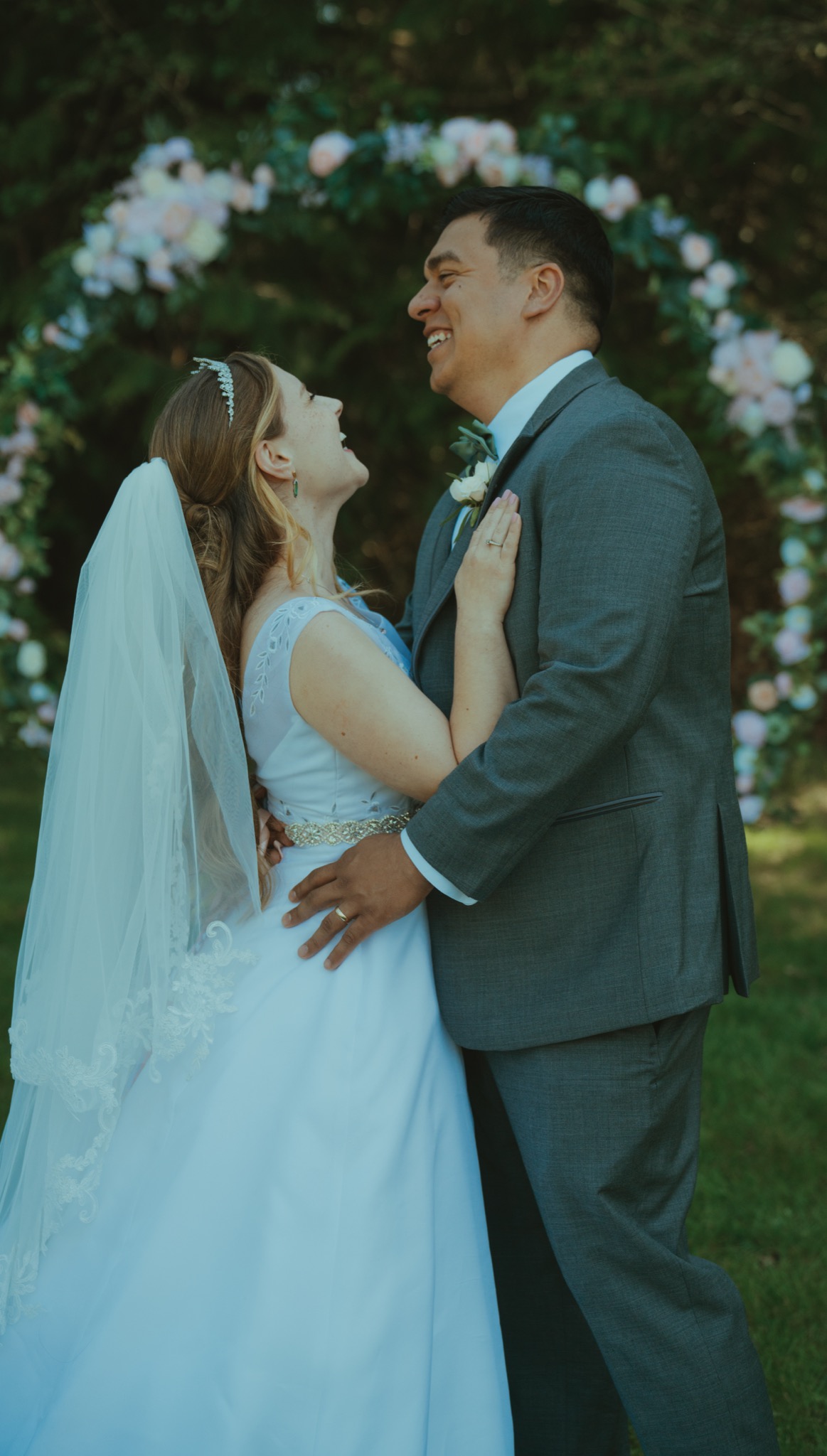 Wedding couple embracing under floral arch