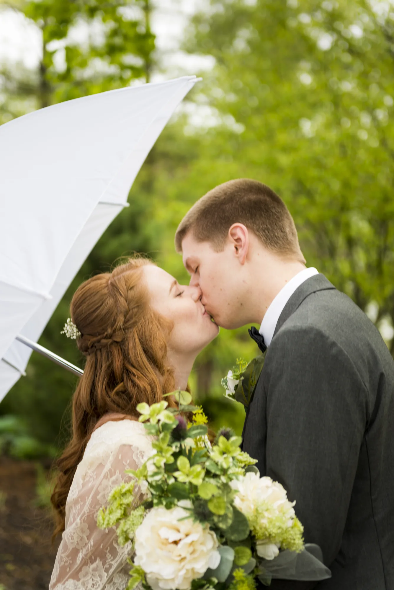 Wedding couple kiss under umbrella with bouquet in Snohomish County