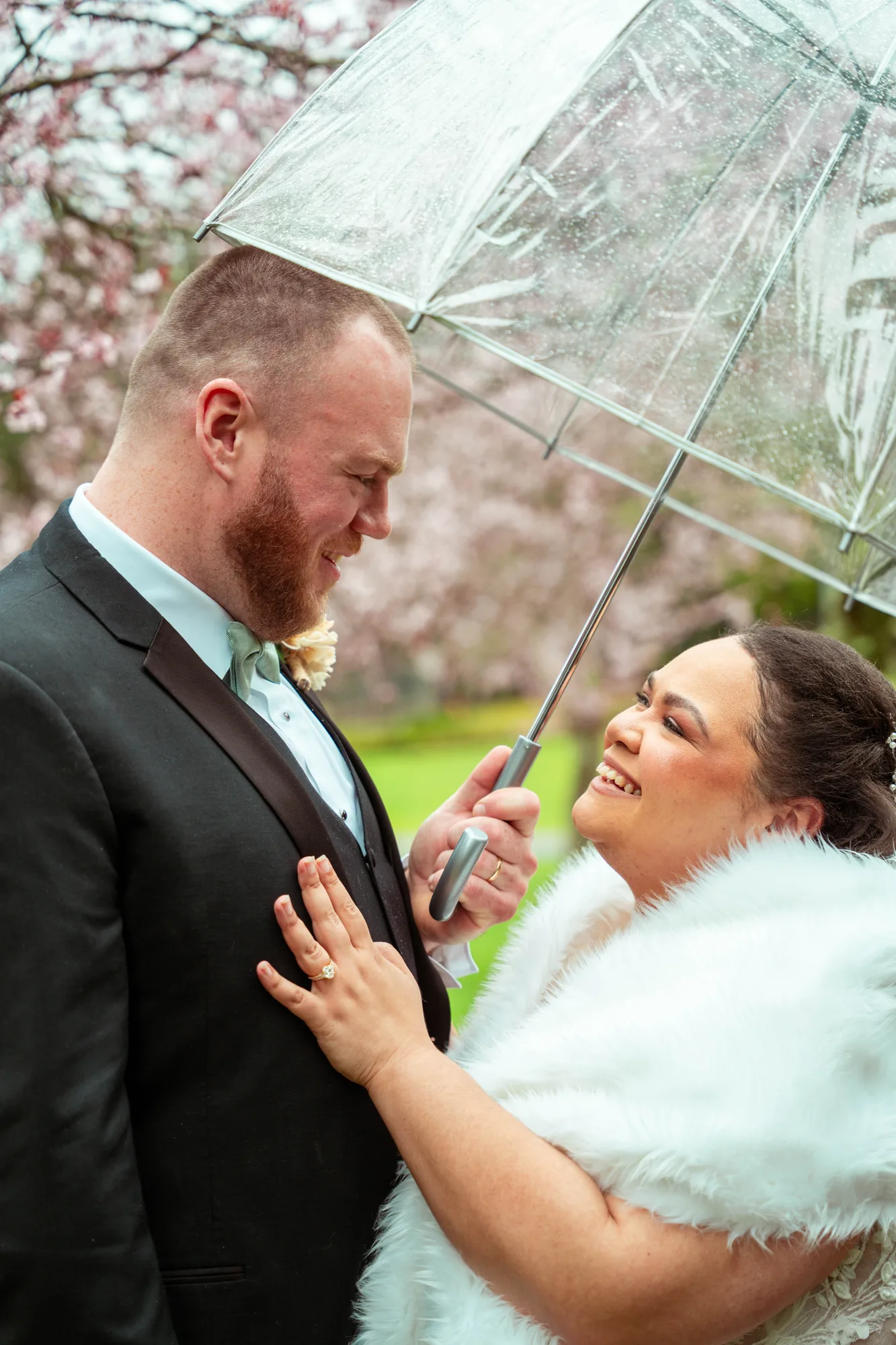 Wedding couple laughing under umbrella with cherry blossoms in Snohomish County