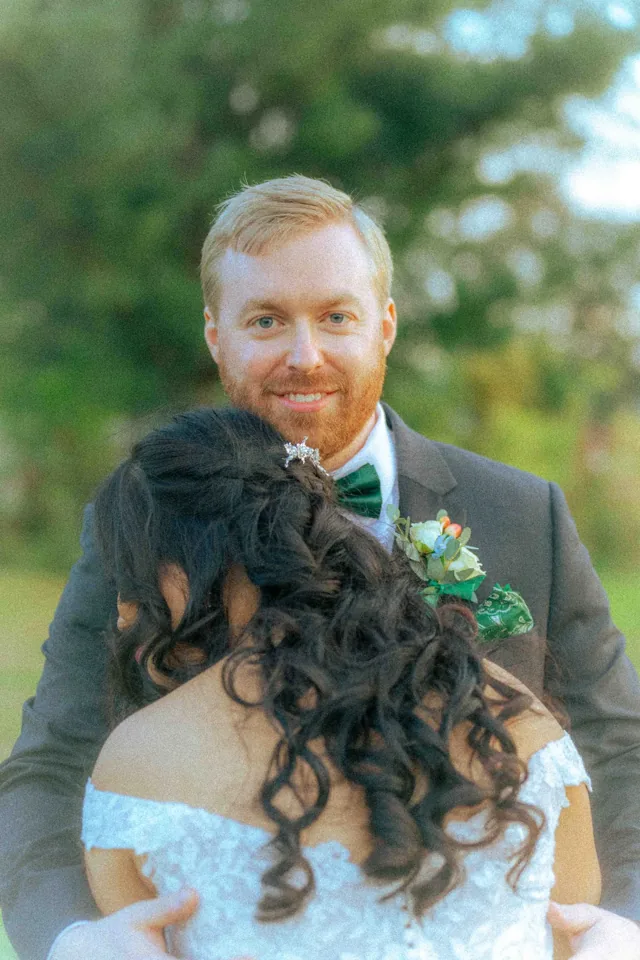 Groom smiling as he embraces his bride in the evening light