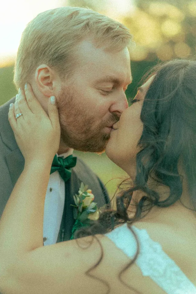Bride and groom sharing a close kiss in warm golden-hour light