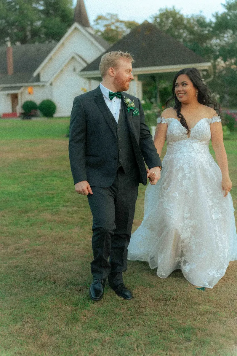 Newlyweds walking hand in hand past a white chapel