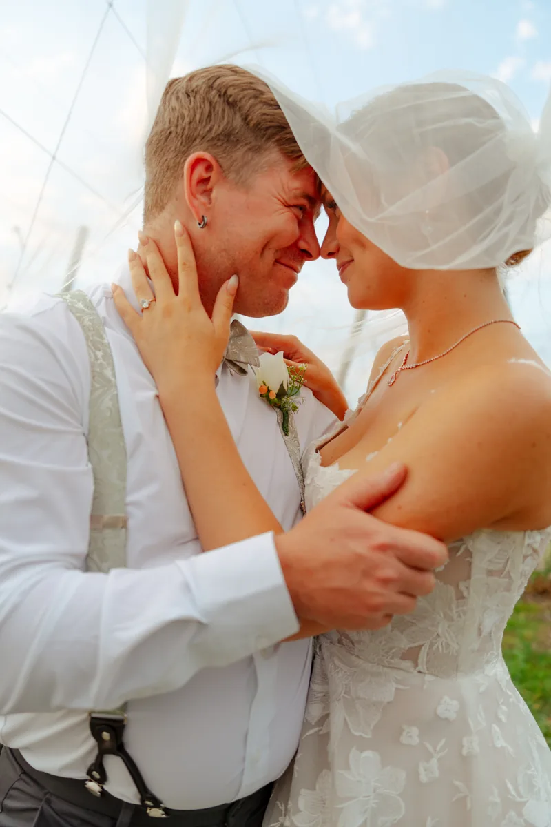 Newlyweds forehead to forehead under the veil in golden light