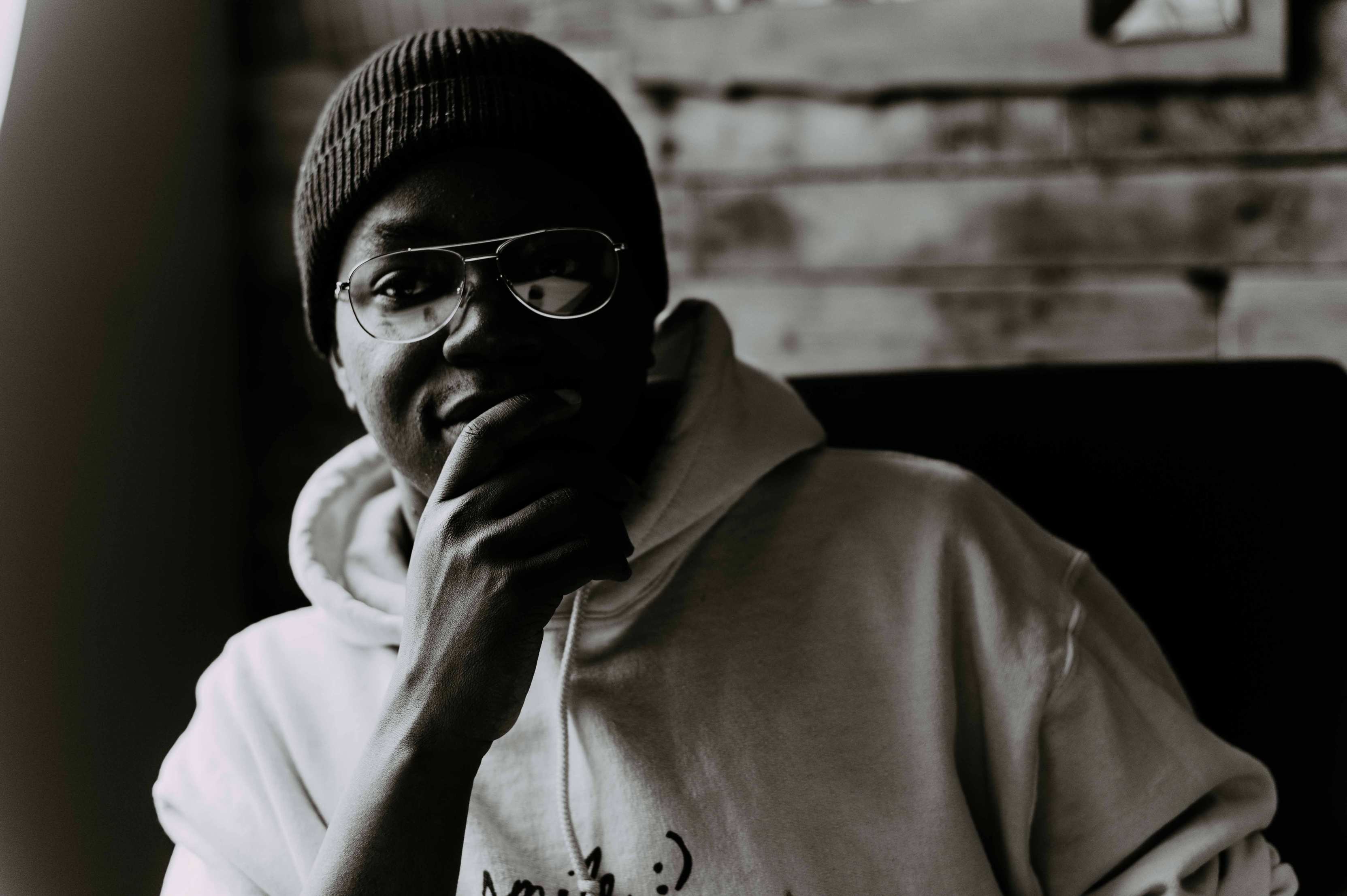 a man in a white hoodie and cap wearing glasses smiling at camera